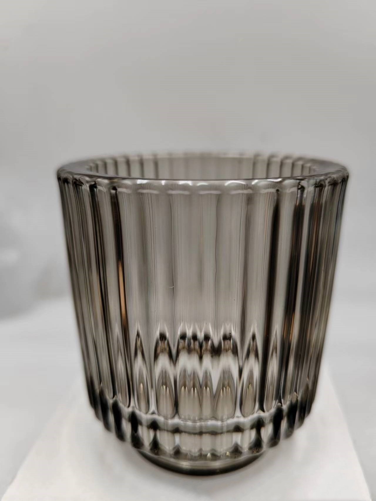 Thick-walled votive glass candle holder with graded color with base stripe