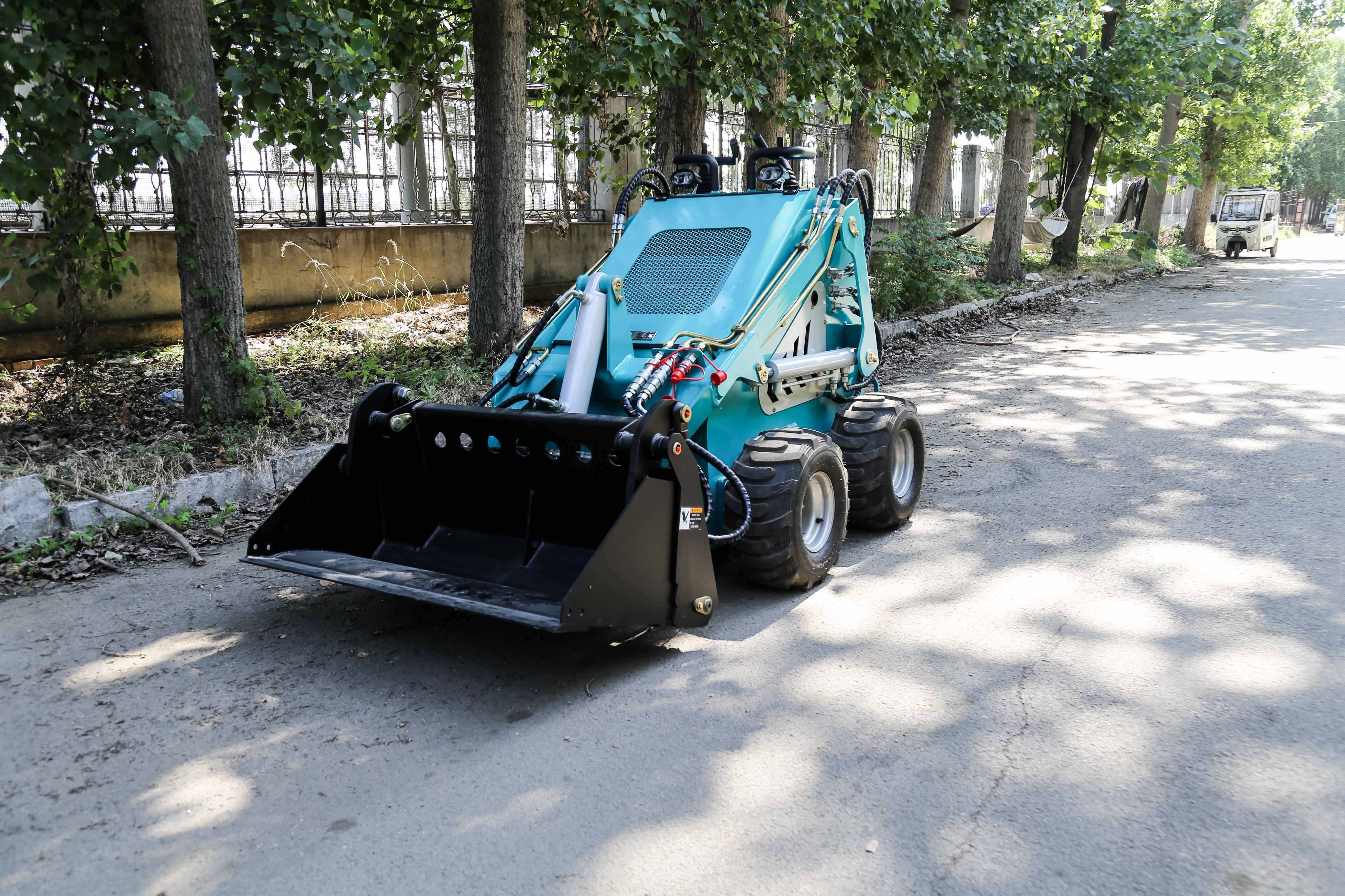 A mini slide loader that can be equipped with various accessories such as a four in one loading bucket trailer, snow sweeper,