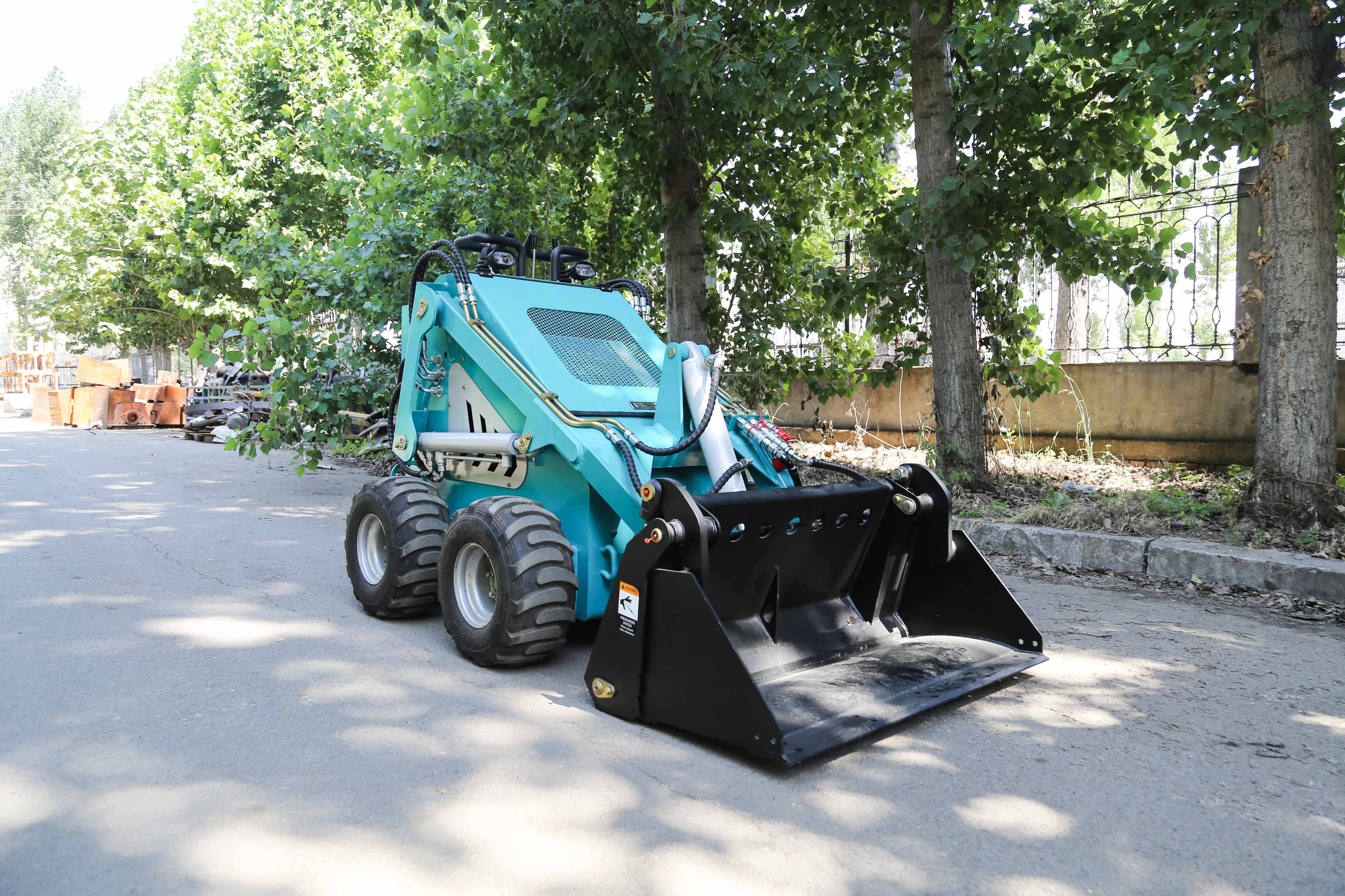 A mini slide loader that can be equipped with various accessories such as a four in one loading bucket trailer, snow sweeper,