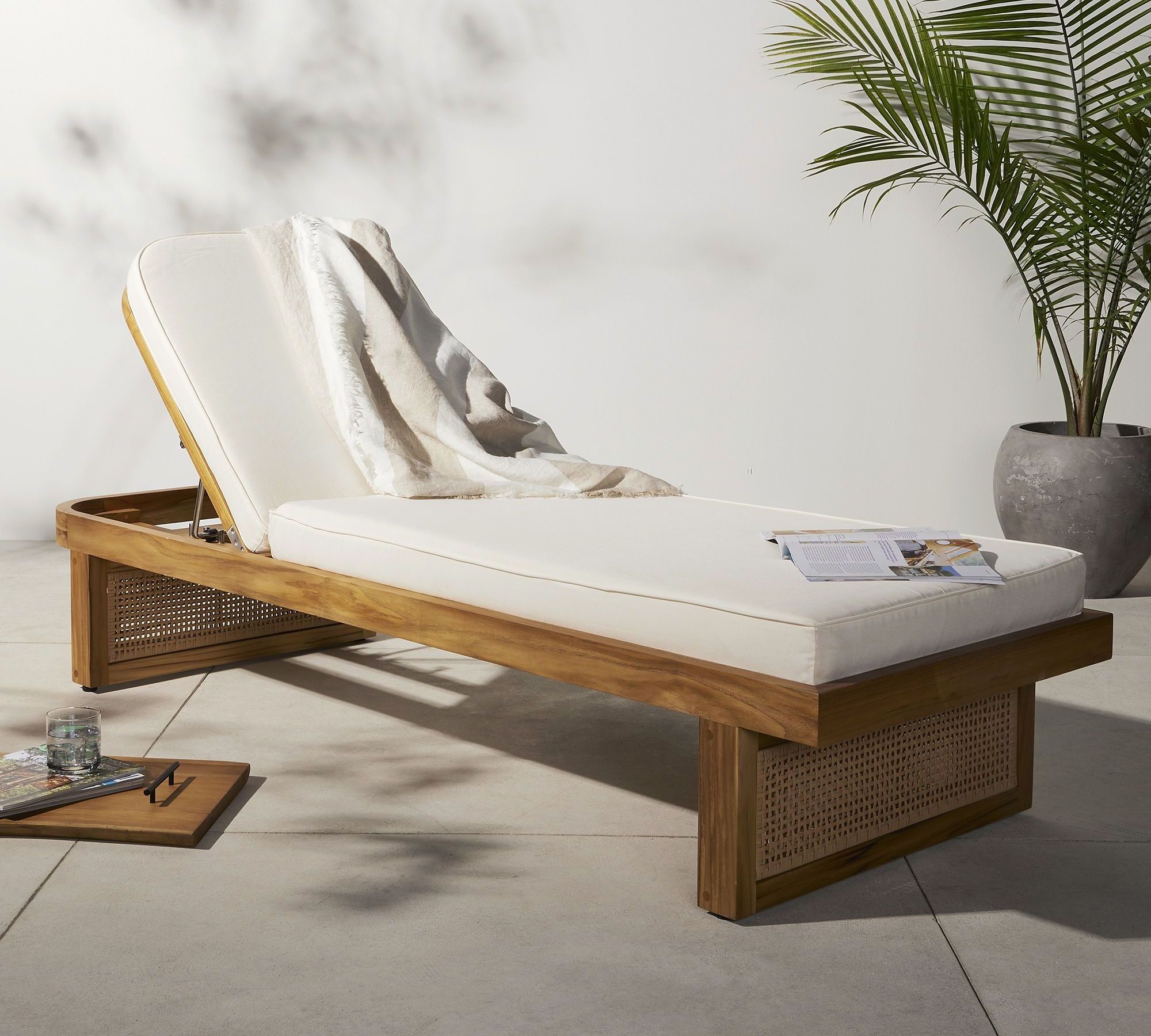 Varicha outdoor chaise chair made from solid teak wood frame and woven rattan legs with thick, water-repellent padding.