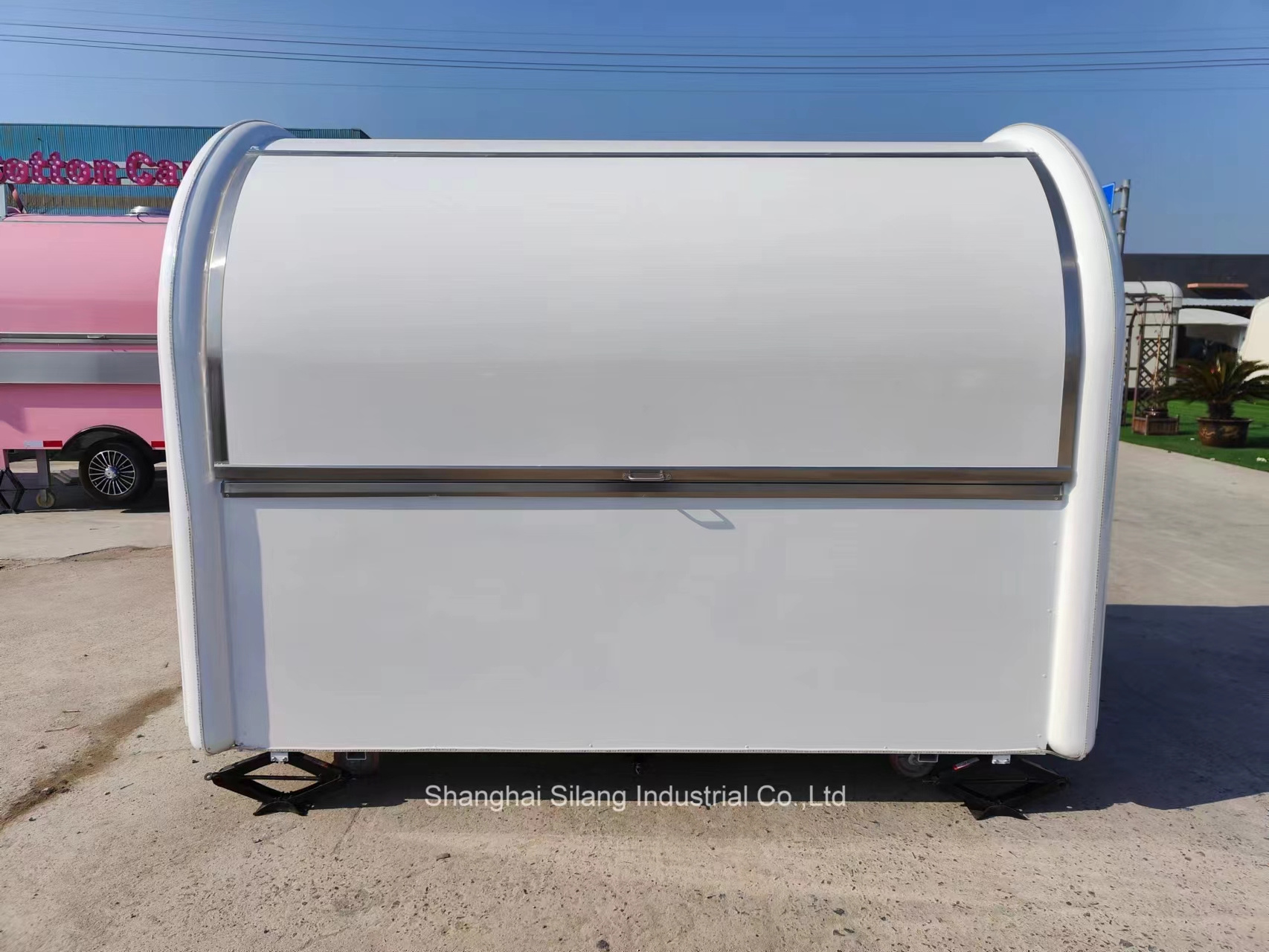 A food truck trailer with white fiberglass and right angle sales windows and air conditioning