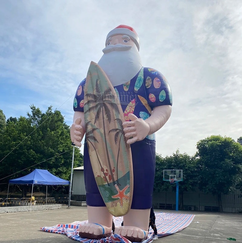 Giant inflatable Santa Claus surfing on the beach outdoors with a skateboard, beach themed Xmas inflatable decoration