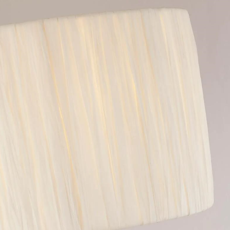 Raffia chandeliers light white drum-shaped lampshades over dining room table or kitchen island